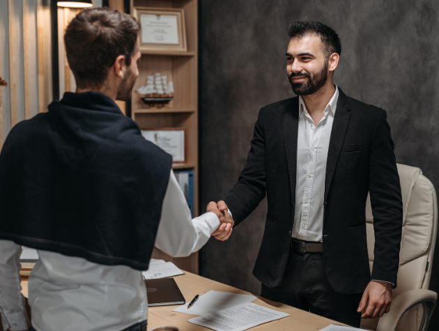Two business professionals shaking hands over a contract, symbolizing successful negotiation and effective communication in business and law.