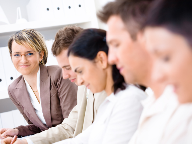 A professional woman , explaining a concept to a small group of colleagues. She’s poised and engaged to communicate clearly. The vibe blends teaching and corporate advising.