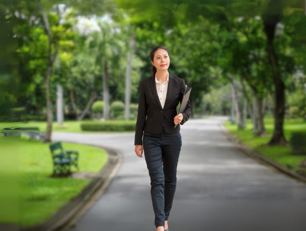 A confident female lawyer walking down a winding path surrounded by trees, symbolizing a nonlinear but purposeful legal journey