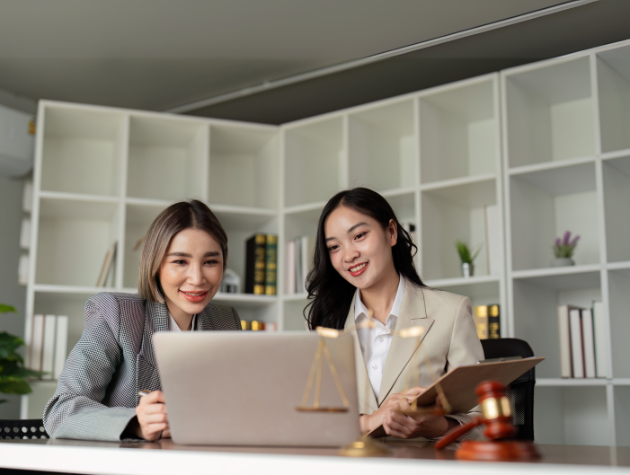 Two female lawyers discussing FTC AI regulation compliance strategies in a modern law office.