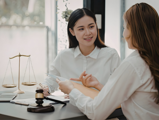 Two legal professionals discussing documents during a mentorship conversation in a corporate legal office